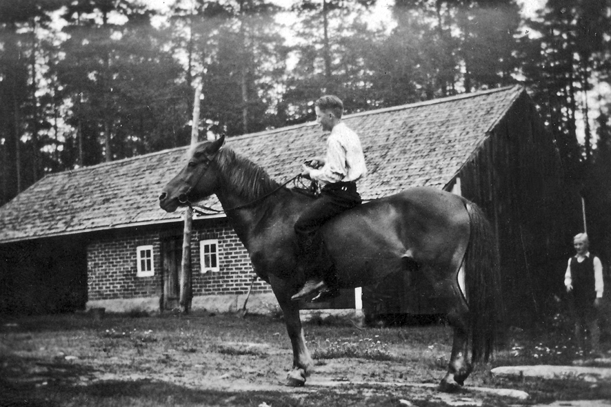 Heikki Mäkelä ratsastamassa Kaunismäen navetan edessä 1940-luvulla korjHL WP